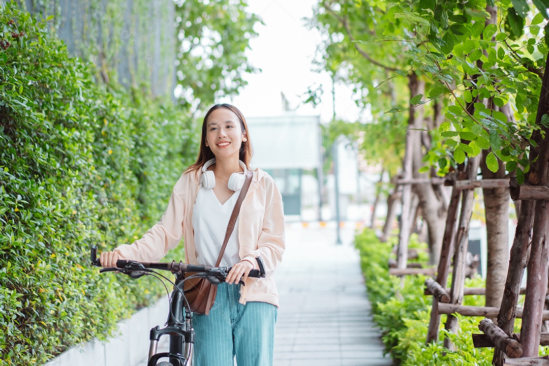 Uma jovem asiática feliz anda de bicicleta no parque