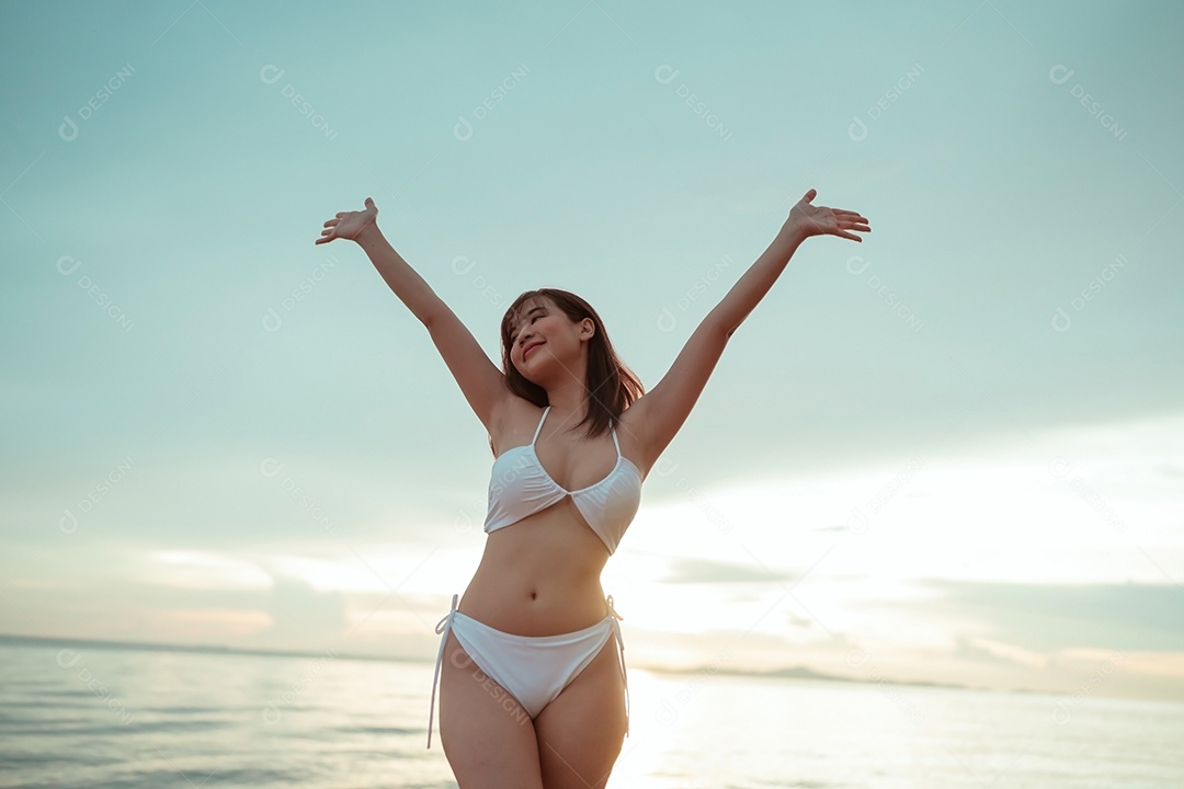 Jovem mulher asiática sorridente na praia tropical descansando e relaxando