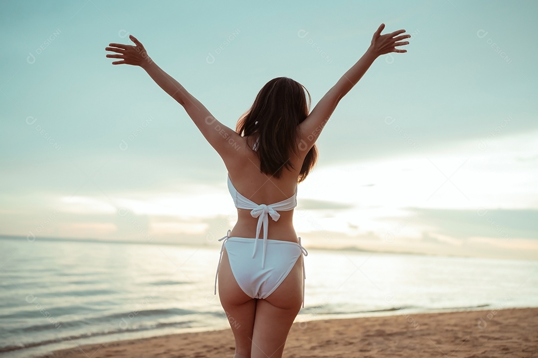 Jovem mulher asiática sorridente na praia tropical descansando e relaxando