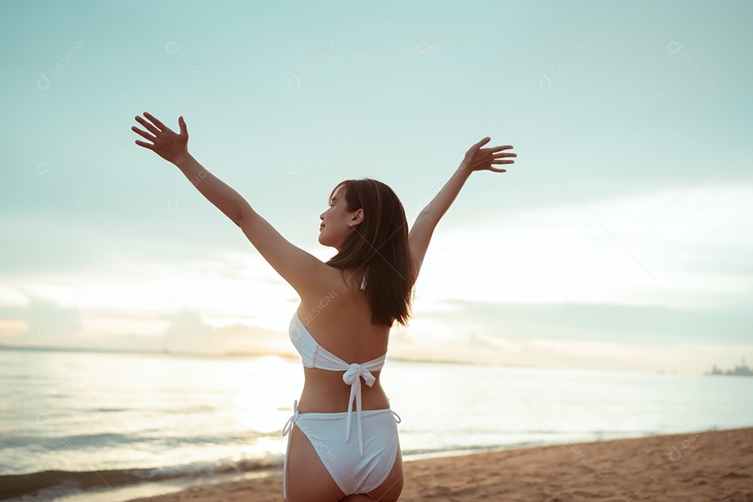 Jovem mulher asiática sorridente na praia tropical descansando e relaxando