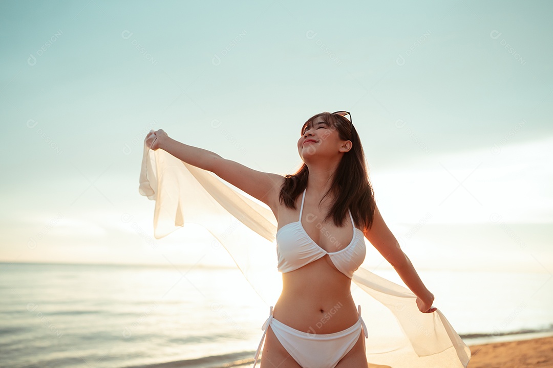 Jovem mulher asiática sorridente na praia tropical descansando e relaxando