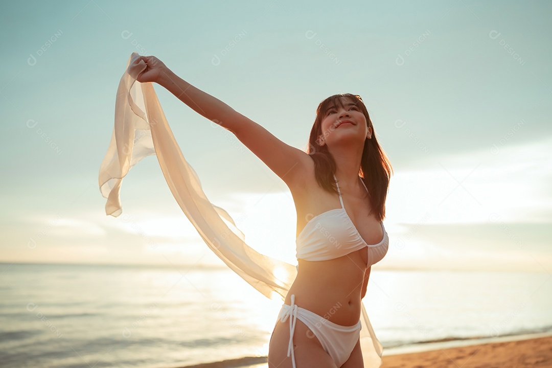 Jovem mulher asiática sorridente na praia tropical descansando e relaxando