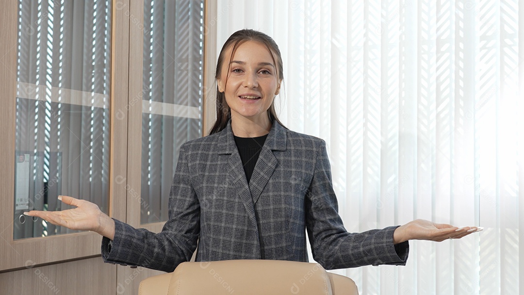 Mulher de negócios que está olhando para a câmera, apresentando o projeto com videoconferência no escritório