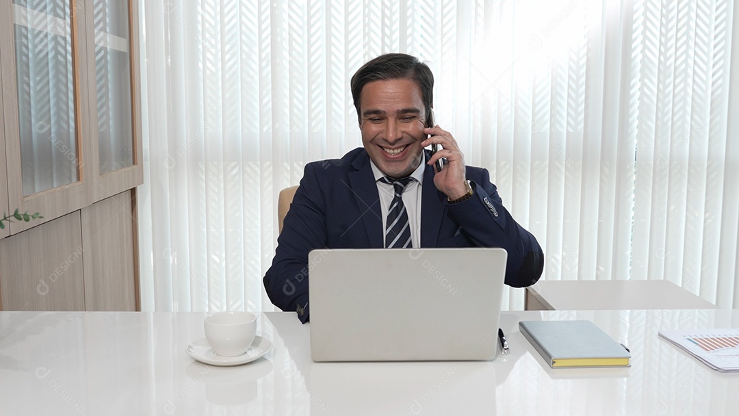 Homem de negócios feliz sorrindo bebendo um café enquanto olha para seu laptop