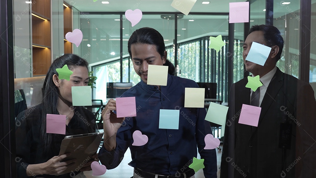 Homem de negócios jovem com brainstorming de trabalho em equipe usando post-its para compartilhar ideias na parede de vidro