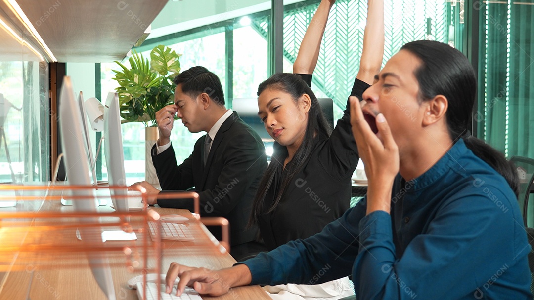 Empresário cansado bocejando enquanto trabalhava no laptop no escritório