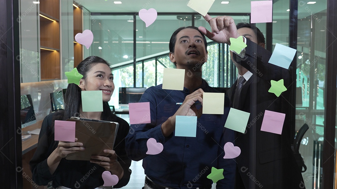 Funcionários escrevendo pequenos lembretes e colando sobre vidro