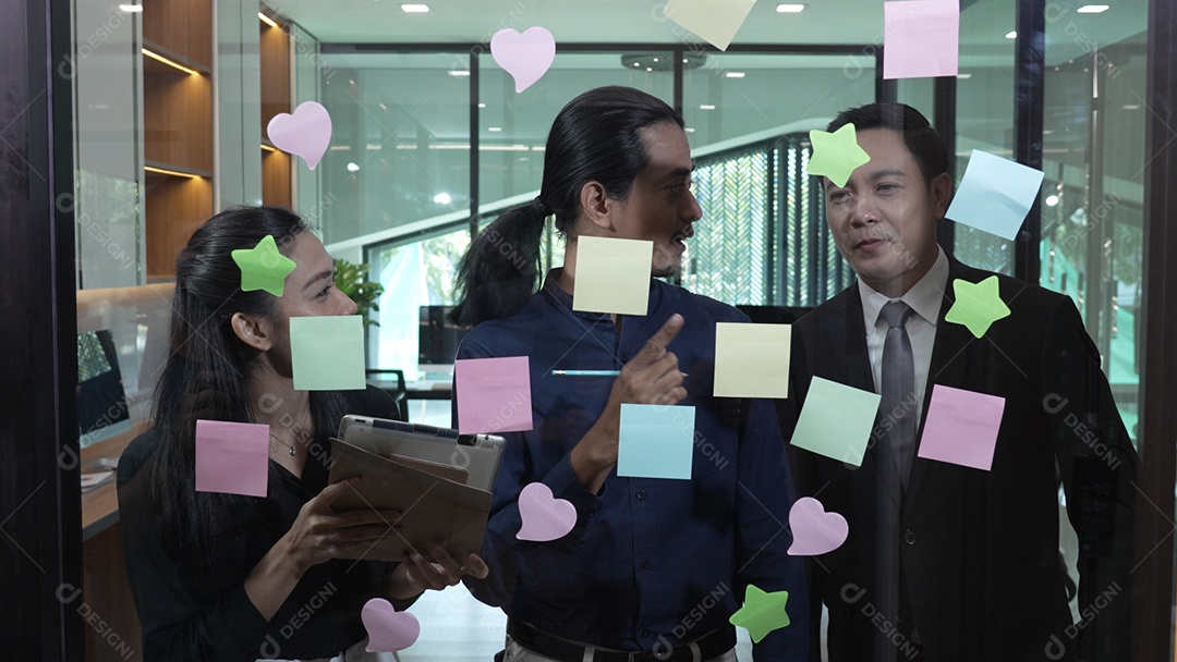 Funcionários escrevendo pequenos lembretes e colando sobre vidro