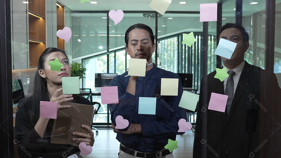 Funcionários escrevendo pequenos lembretes e colando sobre vidro