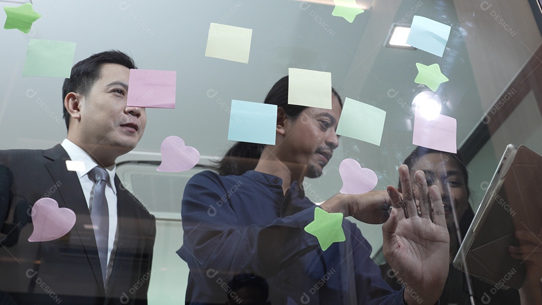 Funcionários escrevendo pequenos lembretes e colando sobre vidro