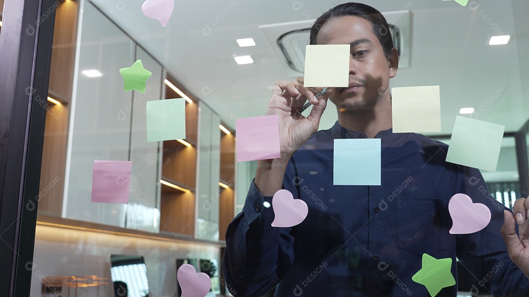 Homem escrevendo pequenos lembretes e colando sobre vidro