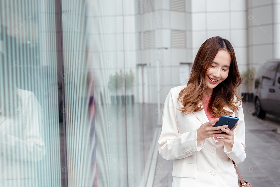 Linda empresária asiática usa smartphone segurando copo de papel com bebida quente