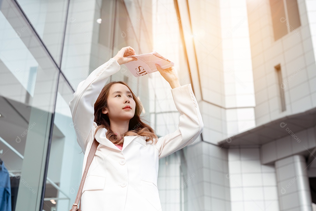 A emoção de estresse da empresária asiática pega o jornal cobre o rosto