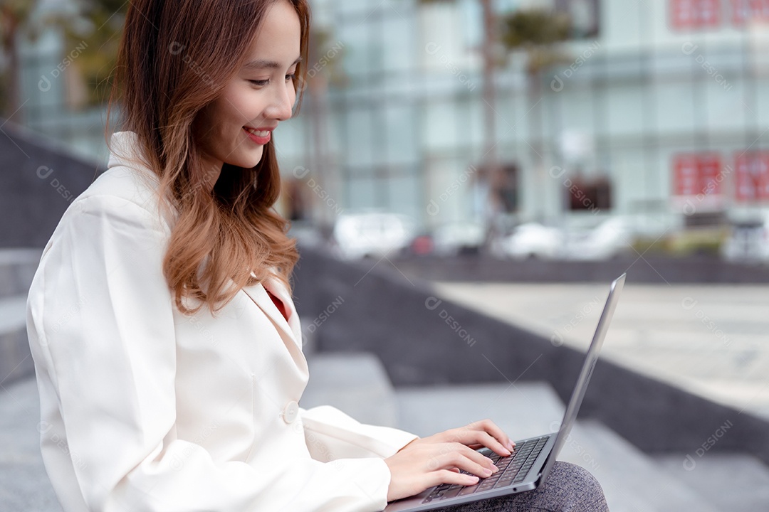 Empresária asiática usa computador portátil e teclado de digitação