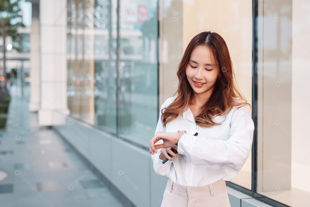 A empresária asiática sorridente segura o celular portátil