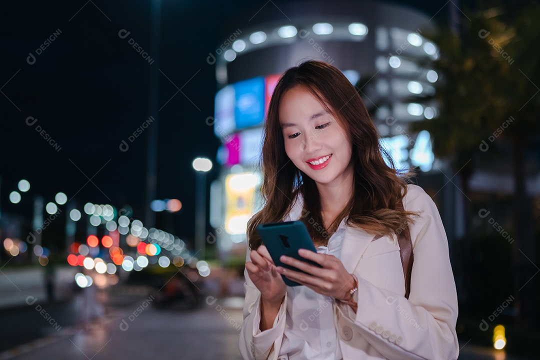 Encantadora empresária asiática usa telefone celular na cidade à noite