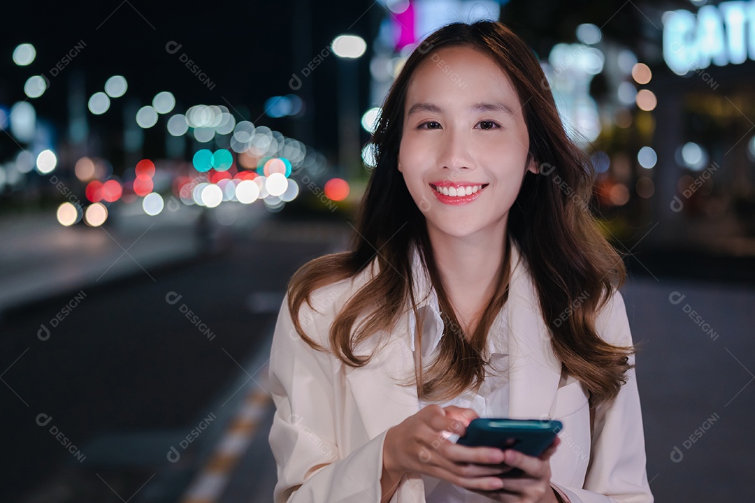 Encantadora empresária asiática usa telefone celular na cidade à noite