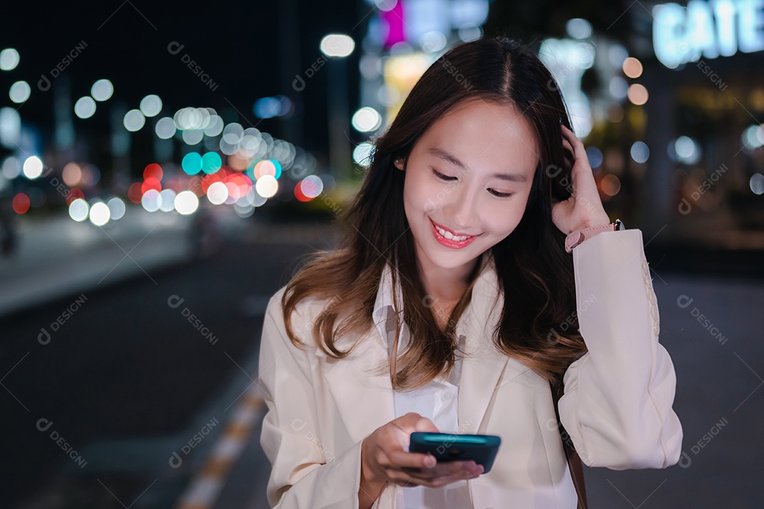 Encantadora empresária asiática usa telefone celular na cidade à noite