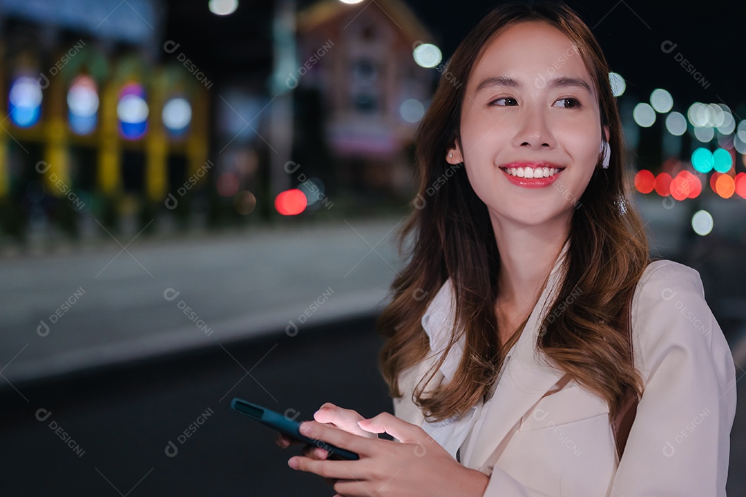 Encantadora empresária asiática usa telefone celular na cidade à noite