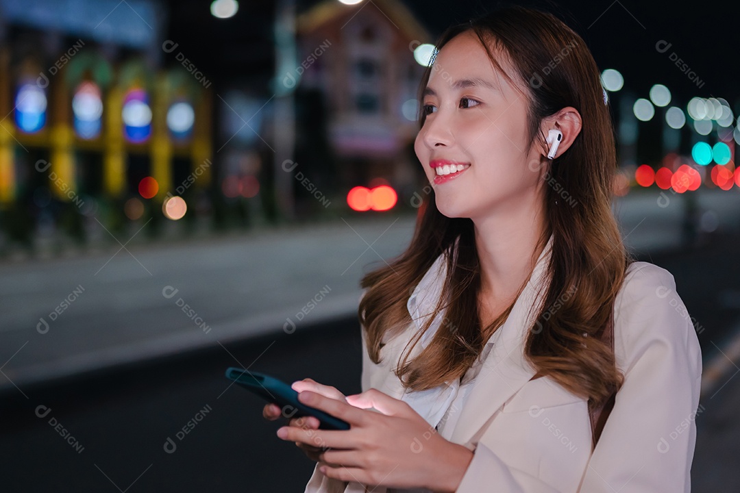 Encantadora empresária asiática usa telefone celular na cidade à noite