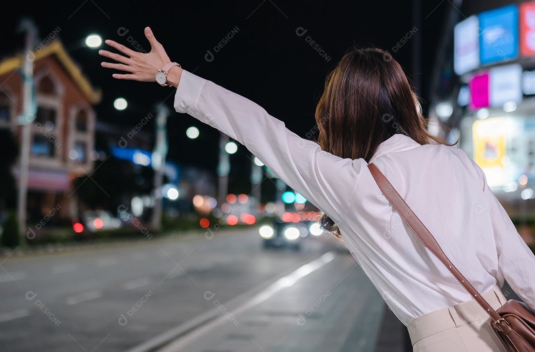 Empresária asiática usa telefone celular para chamar táxi em aplicativo na rua da cidade à noite