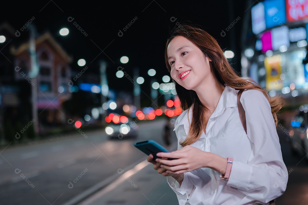 Encantadora empresária asiática usa telefone celular na cidade à noite