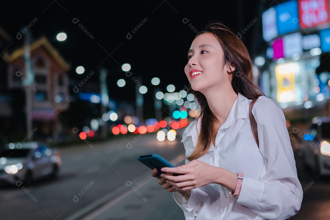 Encantadora empresária asiática usa telefone celular na cidade à noite
