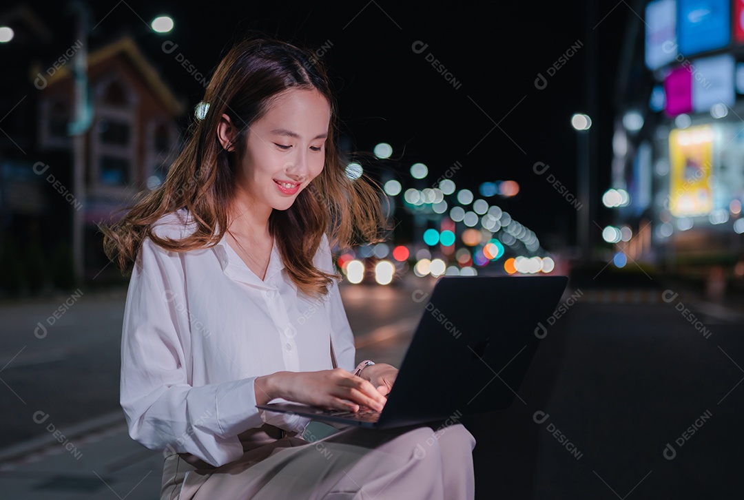 Encantadora empresária asiática usa telefone celular na cidade à noite