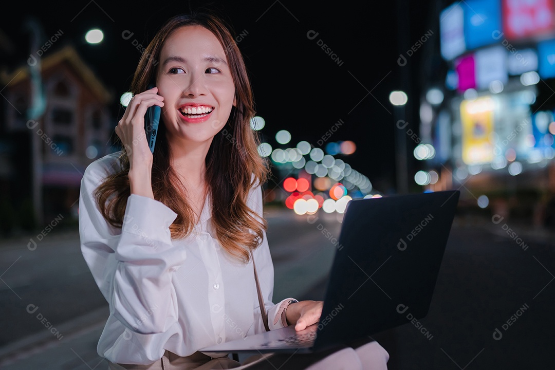 Encantadora empresária asiática usa laptop na cidade à noite