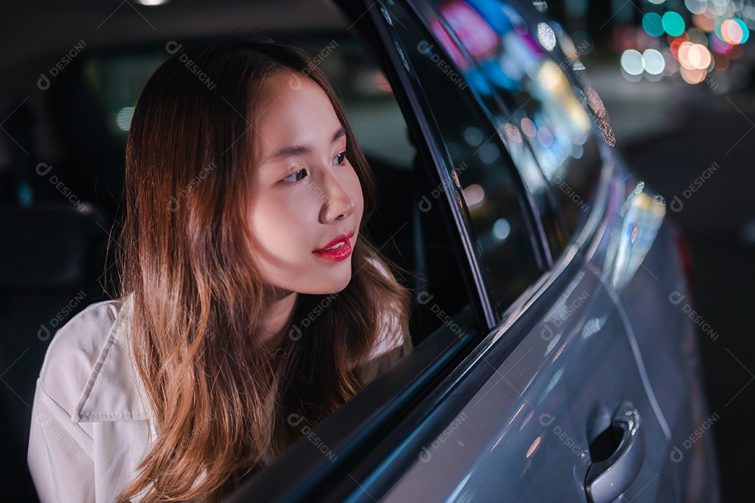 Sorrindo da empresária asiática bem-sucedida, use o smartphone móvel sentado no banco de trás do carro