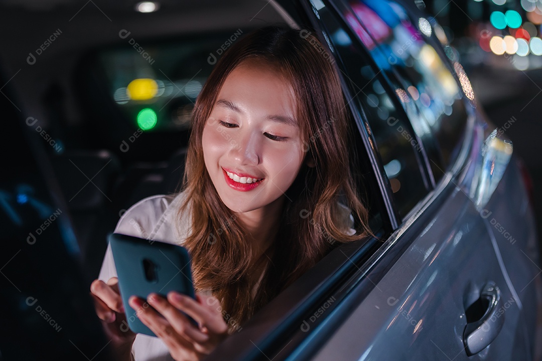 Empresária asiática de sucesso, sentada no banco de trás do carro