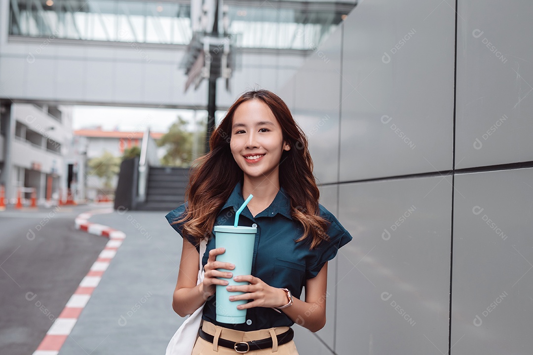 Empresária asiática sorridente segura copo ecológico reutilizável