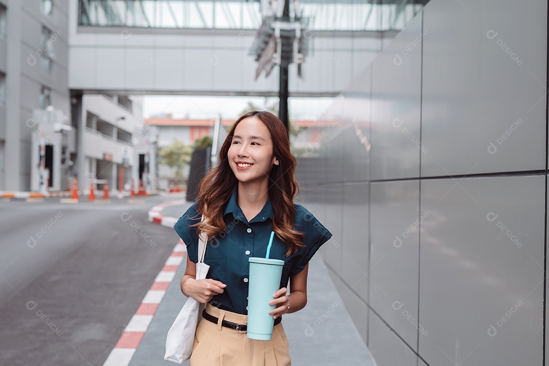 Empresária asiática sorridente segura copo ecológico reutilizável