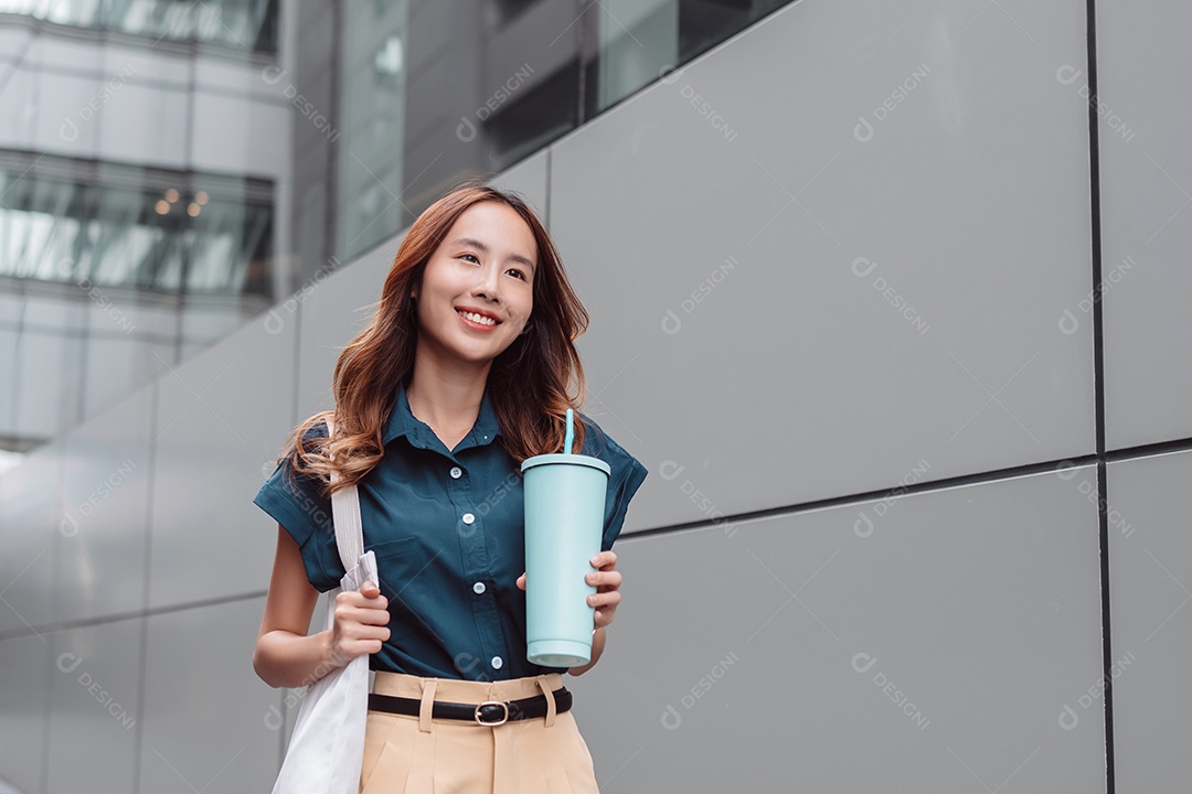 Empresária asiática sorridente segura copo ecológico reutilizável