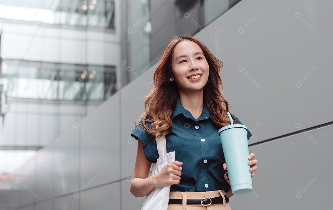 Empresária asiática sorridente segura copo ecológico reutilizável