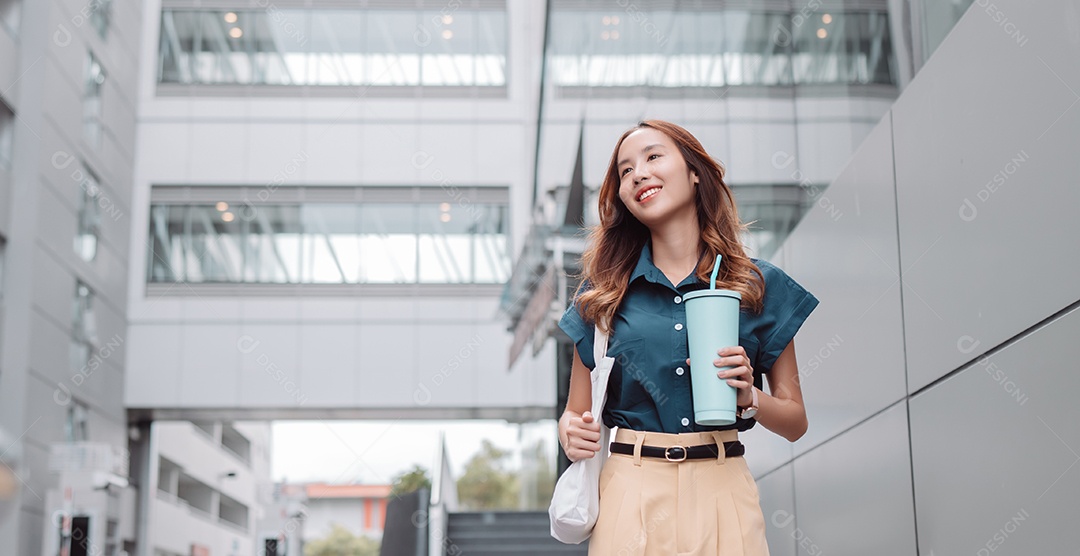 Empresária asiática sorridente segura copo ecológico reutilizável
