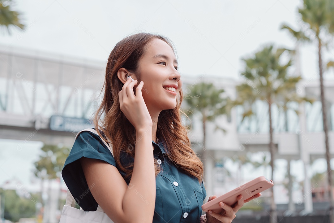 Empresária asiática usa fones de ouvido sem fio ouvindo música