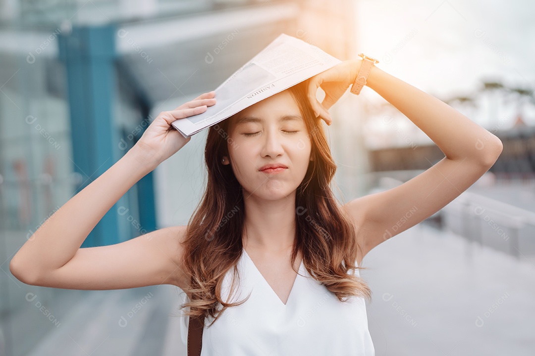 A emoção de estresse da mulher asiática pega o jornal cobre o rosto do sol na cidade moderna