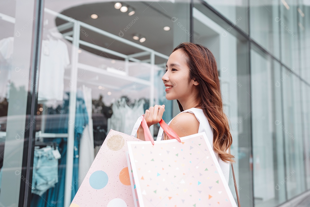 Linda mulher asiática segurando sacolas de compras