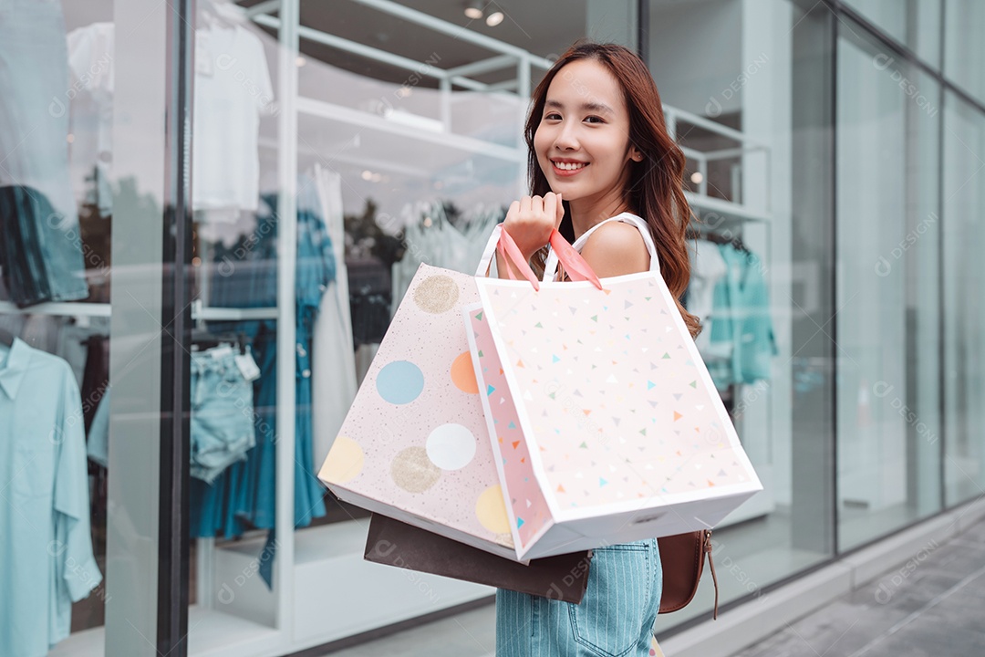 Linda mulher asiática segurando sacolas de compras