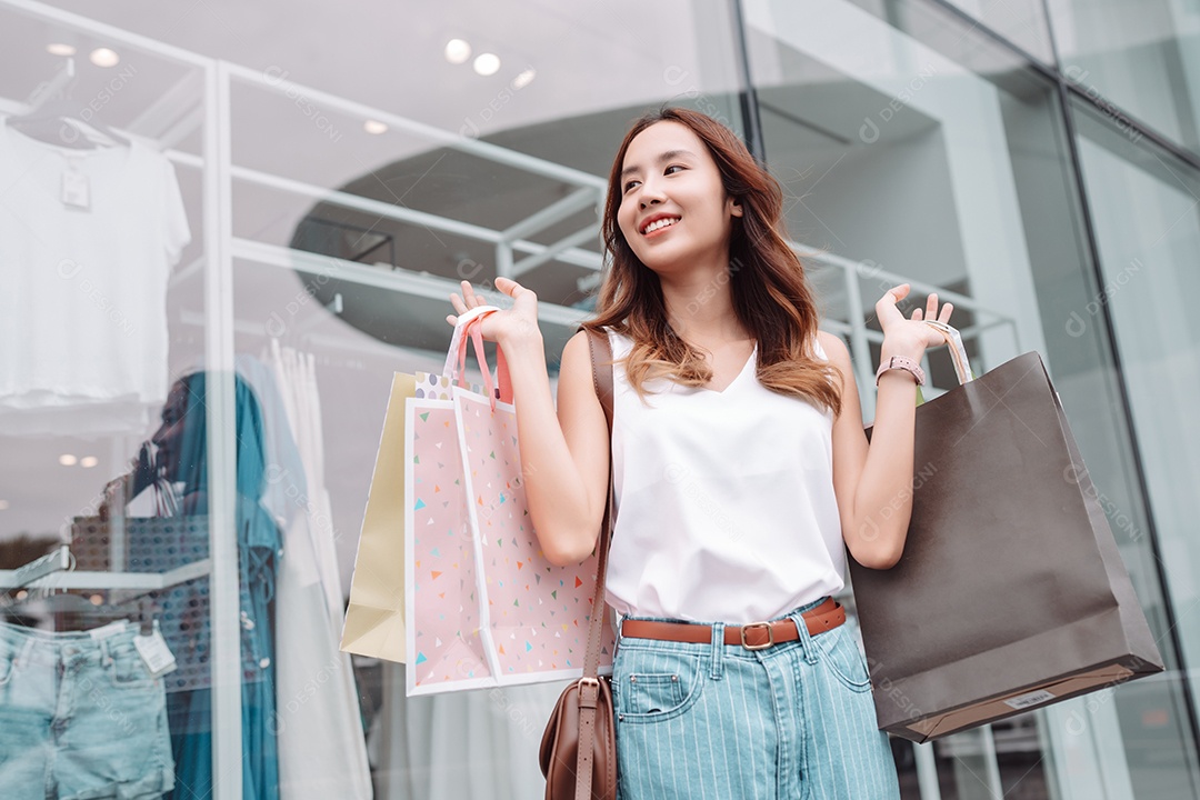 Linda mulher asiática segurando sacolas de compras
