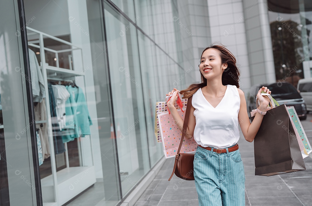 Linda mulher asiática segurando sacolas de compras