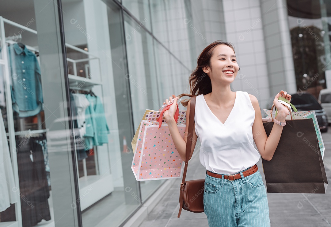 Linda mulher asiática segurando sacolas de compras