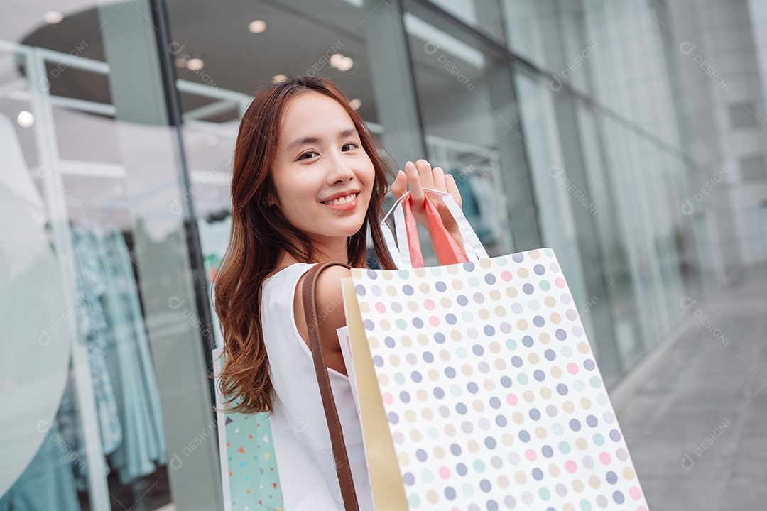 Linda mulher asiática segurando sacolas de compras