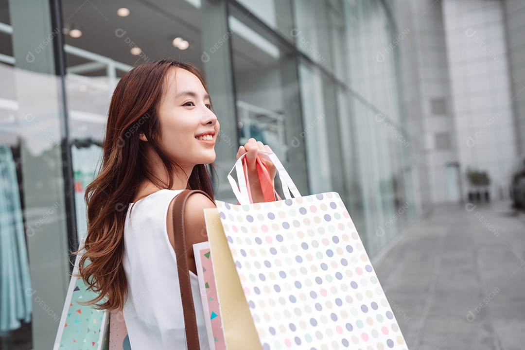 Linda mulher asiática segurando sacolas de compras