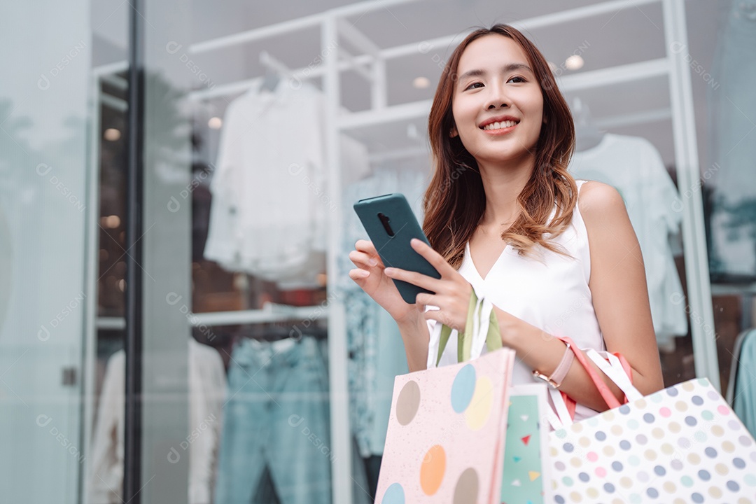 Linda mulher asiática segurando sacolas de compras