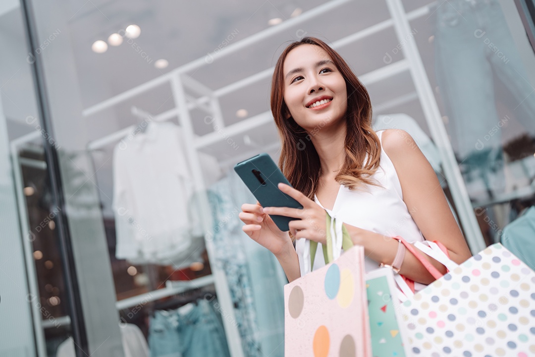 Linda mulher asiática segurando sacolas de compras