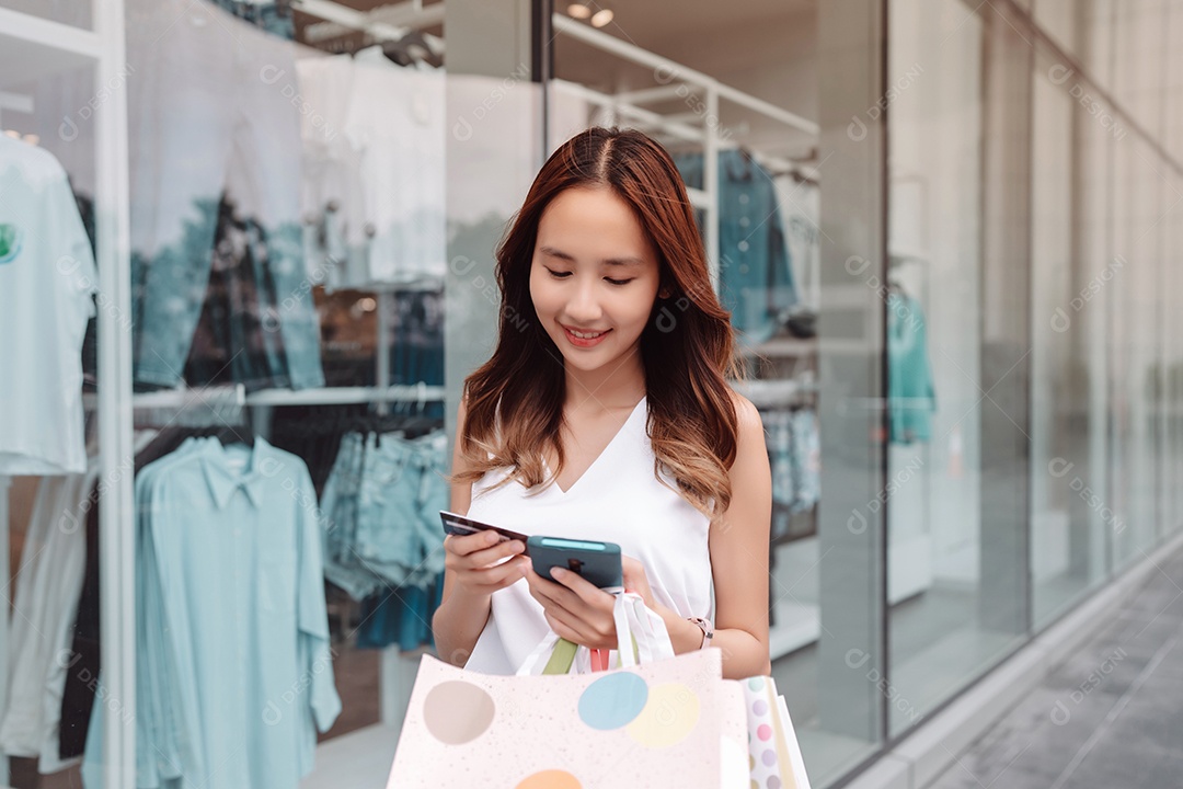 Mulher asiática cliente compradora usando cartão de crédito e smartphone para pagamento
