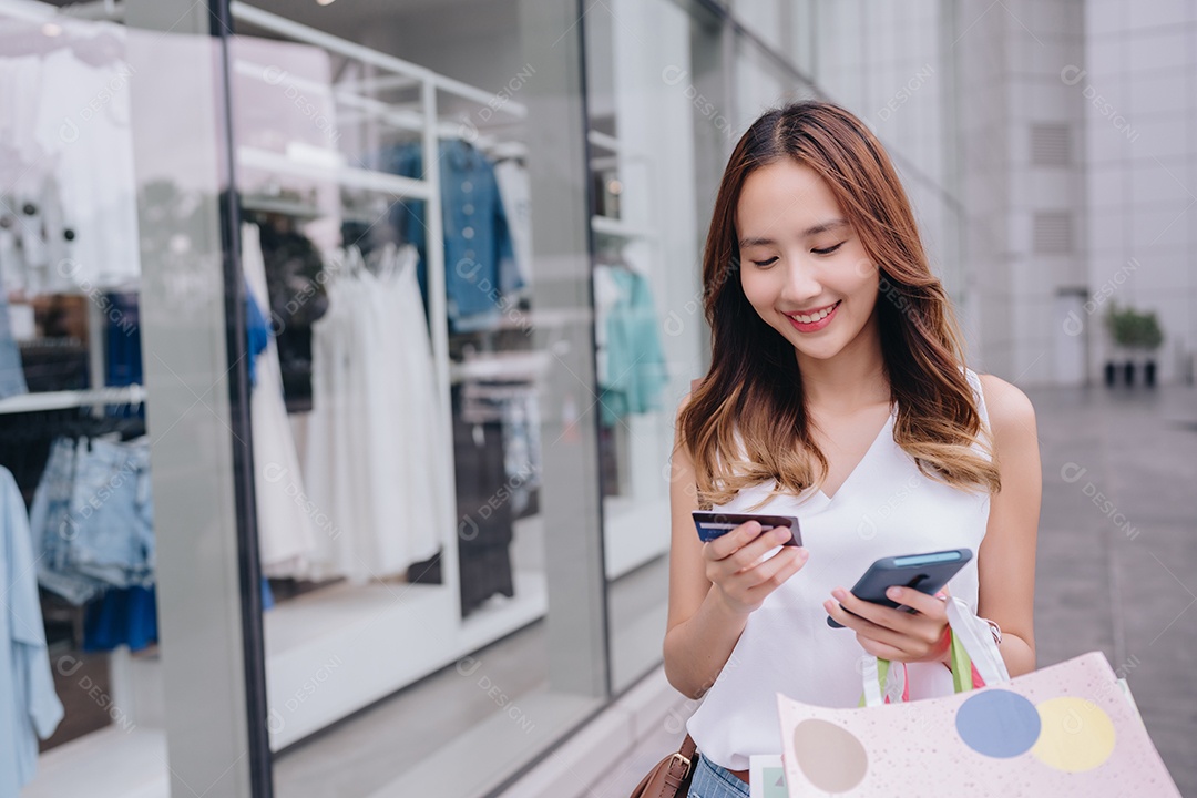 Mulher asiática cliente compradora usando cartão de crédito e smartphone para pagamento