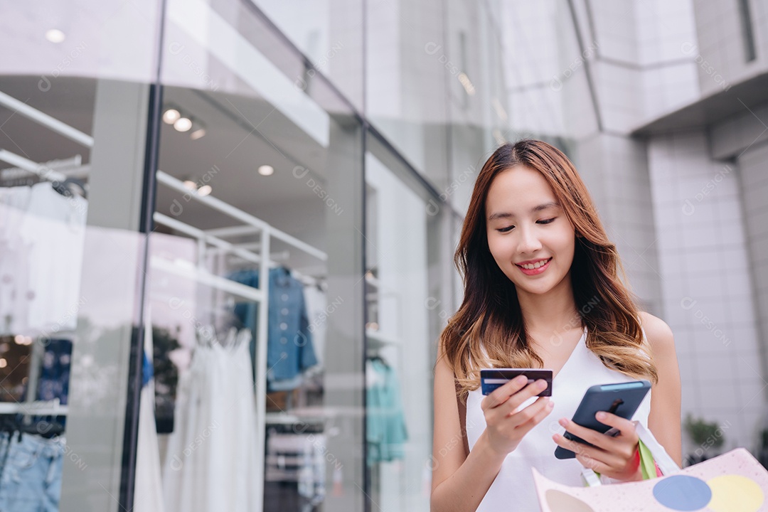 Mulher asiática cliente compradora usando cartão de crédito e smartphone para pagamento